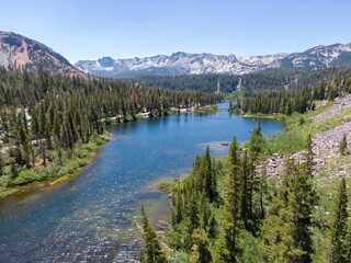 Aerial view of Twin Lakes in Mammoth Lakes, California, USA. The lake is surrounded by pine trees and mountains. The photo was taken on a sunny day.