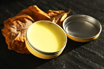 Natural solid perfume and dry leaf on black table, closeup