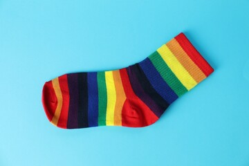 One sock in LGBT colors on light blue background, top view