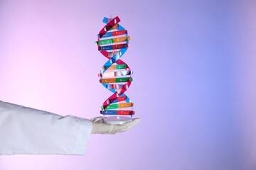 Scientist with DNA structure model on color background, closeup