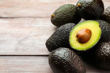 Fresh ripe avocados on light wooden table, closeup. Space for text