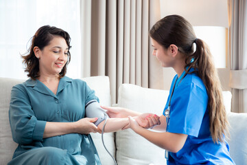 Obraz premium Caregiver caucasian young nurse woman measuring blood pressure with patient for checkup pulse health and examining in living room at home, nurse checkup patient for health care, medical and insurance.