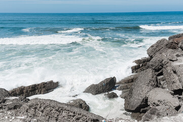 Powerful waves crash against the rocky coastline, 