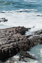 Rocky shoreline with powerful waves crashing against the jagged rocks.  