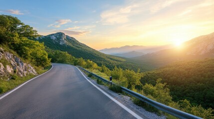 Scenic mountain road at sunset, winding through lush green landscape.