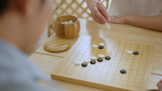 Close up of young men play board game Go during competition in community. 