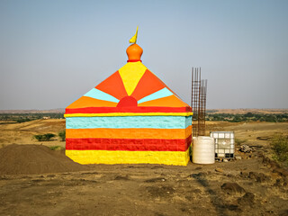 Colorful isolated image of a colorful temple in construction, on the background of nice blue sky in the outskirts of village.