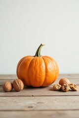 A vibrant orange pumpkin rests on a rustic wooden surface, accompanied by several whole walnuts, creating a simple yet autumnal still life.