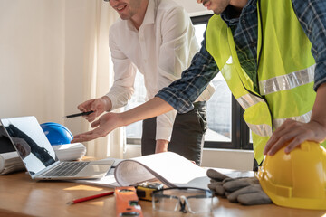 Engineers use laptops and check the blueprint. Contractor review drawing before start project civil. Prepare construction project planning concept. © Shisu_ka