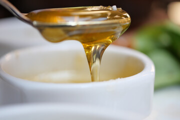 Golden honey dripping from a spoon in a kitchen setting
