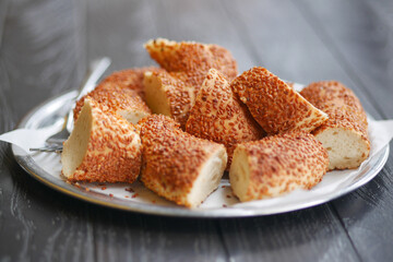 Freshly baked bread rolls topped with sesame seeds on a silver tray