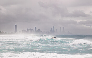 Heavy surf with a personal water craft taking a surfer out to catch a wave, with Surfers Paradise...