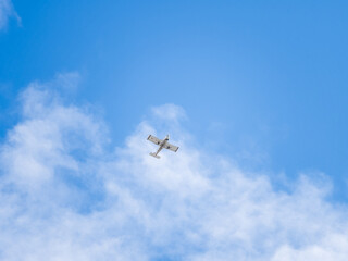 Small ultralight airplane with overhead wing and single propeller flying in sunset sky.