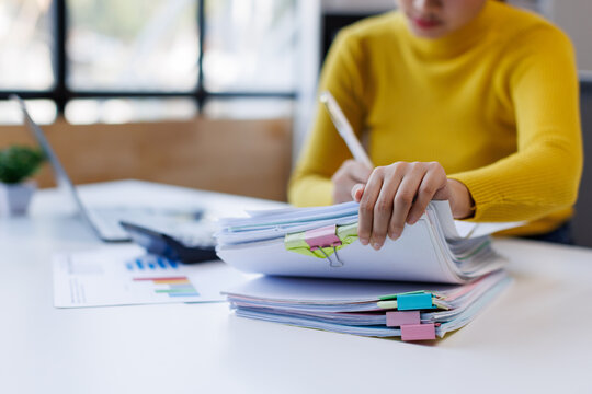 Business asian woman hands working in Stacks of paper files for searching and checking unfinished document achieves on folders papers at busy work desk office
