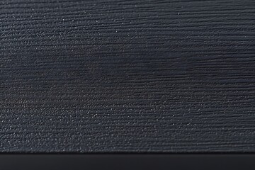 Close-up of dark gray wood grain texture with a black edge.