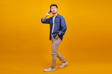 Confident Relaxed Young Adult Male Student Walking And Talking On The Mobile Phone