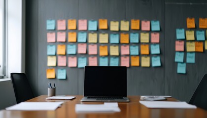 A modern office workspace featuring a laptop, desk and a wall covered in colorful sticky notes.