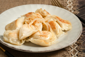 Close up of homemade fried polish pierogi served with fried onion