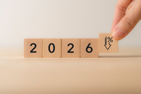 2026 Economic Decline Concept. Wooden blocks displaying "2026," with hand placing a final block with downward arrow and percentage symbol. Economic decline,financial downturns, and market challenges.