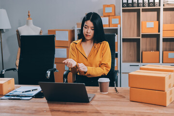 Asian SME business women use laptop computer checking customer order online shipping boxes at home....