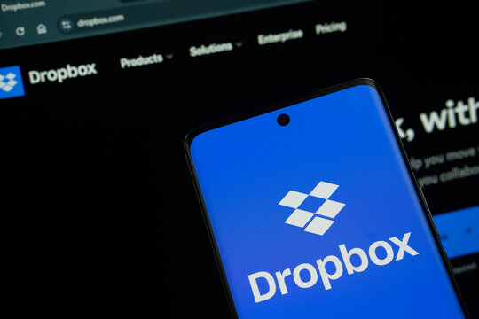 Dhaka, Bangladesh- 05 March 2025: Dropbox logo is displayed on a smartphone screen, with the dropbox website visible on a computer screen in the background.