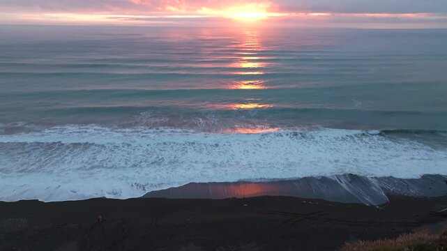 Golden Vibrant sunset California huge swell surf waves orange sun on horizon reflection on Pacific Ocean aerial drone San Francisco Santa Cruz Usal Beach Coastline dusk clouds mist forward pan up