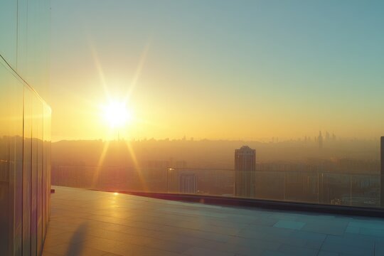 Golden hour cityscape view from a modern rooftop terrace with glass railing.