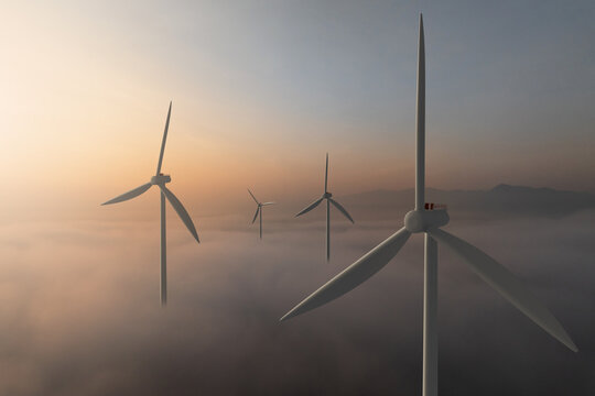 Wind turbine rising above clouds illuminated by sunrise