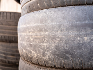Close-up of worn tires with faded tread patterns. The rubber is smooth and weathered, indicating...