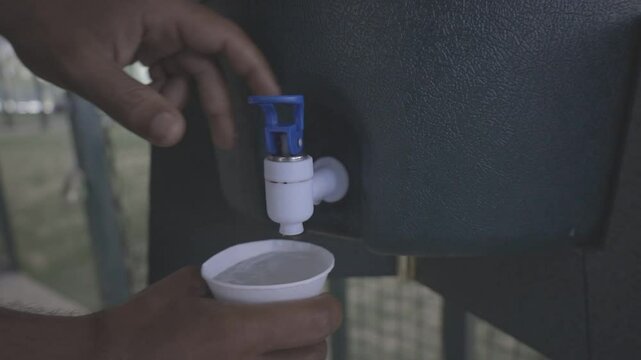 man drinking glass of water at sports drinking fountain, close up shot, raw c-log 8bits video HD