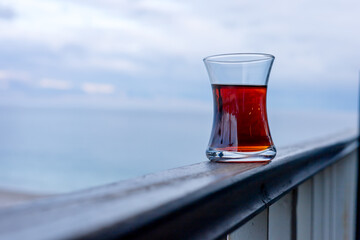 Tea glass on balcony overlooking ocean during cloudy early morning