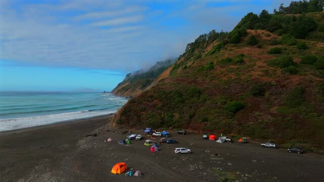 Sunny clear blue skies misty rugged rocky mountainside cliffs bluffs untouched remote USAL Beach campground California aerial drone camping Sinkyone Wilderness Lost Coast Trail upwards motion