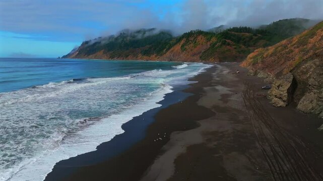 Sinkyone Wilderness sunny clear blue sky misty rugged surf rocky mountainside cliffs bluffs untouched remote USAL Beach campground California aerial drone camping Lost Coast Trail forward pan up