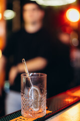 Crystal Glass with Cocktail Strainer on a Bar Counter in Blurred Background