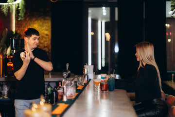 Bartender Serving a Woman Drinks at a Modern Illuminated Bar Counter