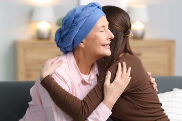 Woman with cancer and her daughter hugging at home
