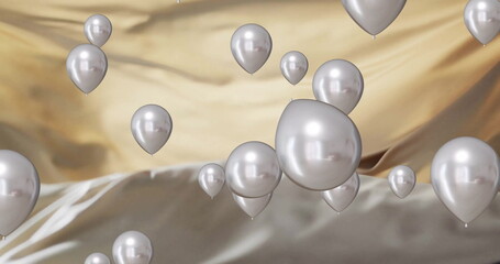 Image of silver balloons floating over gold and black background