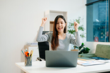 Young attractive Asian woman smiling thinking planning writing in notebook, tablet and laptop working from home