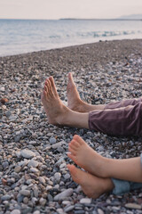 Family relaxation time by the beach with bare feet on rocky shore in the evening light