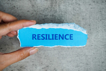 The word 'resilience' in the blue paper rip. Hand Holding blue paper. Business concept.