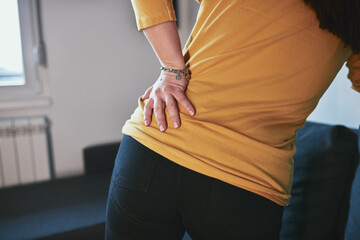 Woman with hip, back and sciatica pain at home.