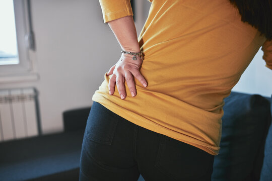 Woman with hip, back and sciatica pain at home.