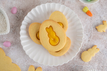 Easter egg-shaped sandwich cookies with orange curd on a white plate on a concrete background. Easter dessert. Top view.
