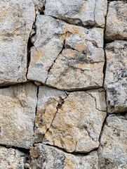 Fototapeta premium Stone Wall Texture: Weathered and textured stone wall, featuring an aged, rough surface, revealing details of the material's natural variation and resilience.