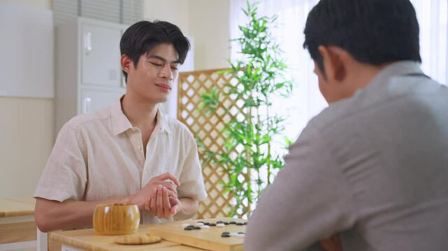 Asian young men playing board game Go during competition in community. 