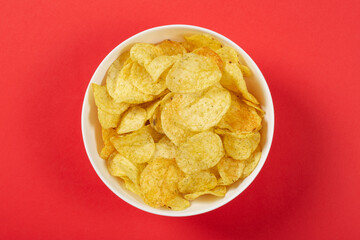 Potato chips in a bowl on red background