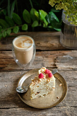 Piece of Napoleon cake with raspberry on a wooden background. Side view.