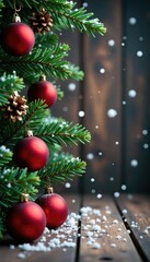 Snowflakes fall gently on a wooden surface adorned with red Christmas ornaments and evergreen branches, branch decor, winter scene, snowflakes