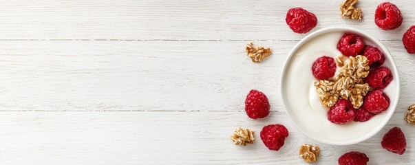 Fototapeta premium A bowl of yogurt topped with fresh raspberries and crunchy granola, set against a light wooden background.