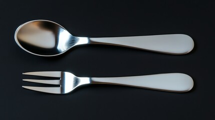 A baby spoon and fork set with rounded edges on a black background